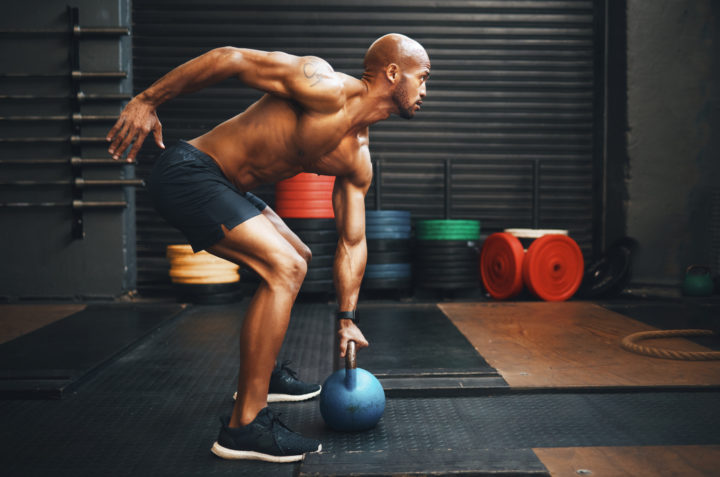 muscular man uses nitric oxide boosters for ehanced energy and lifts kettlebells